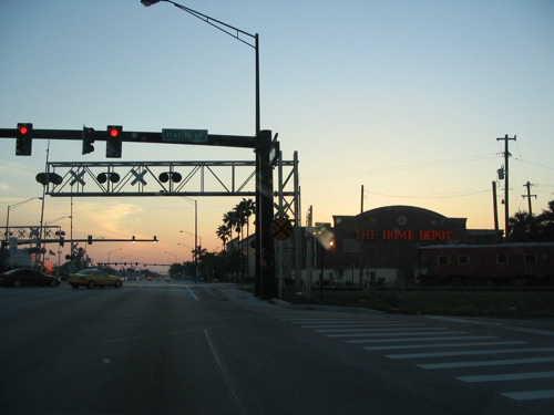 a road that has stop lights, buildings and a street sign on it
