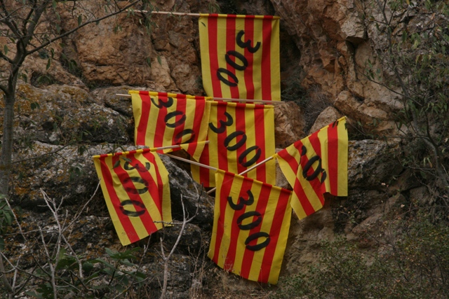 four flags attached to ropes near some rocky cliffs