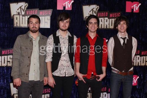 three men standing next to each other on a red carpet