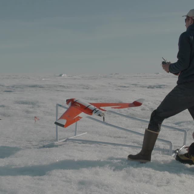 an orange and white plane on ice behind a man