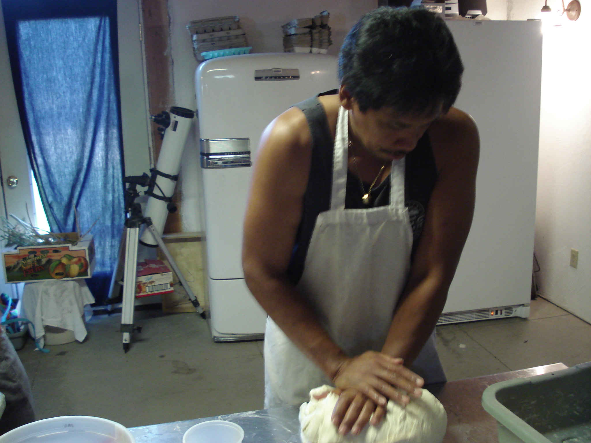 a man kneads dough in an industrial kitchen