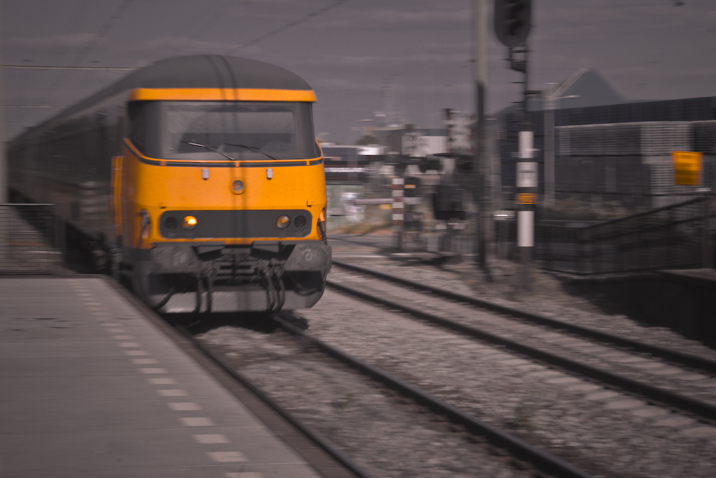 a yellow train traveling down train tracks near a platform