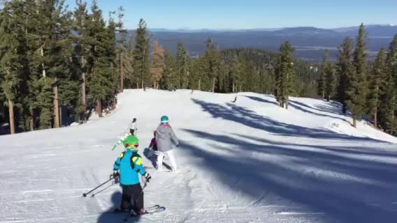 two people wearing skis walking up the hill