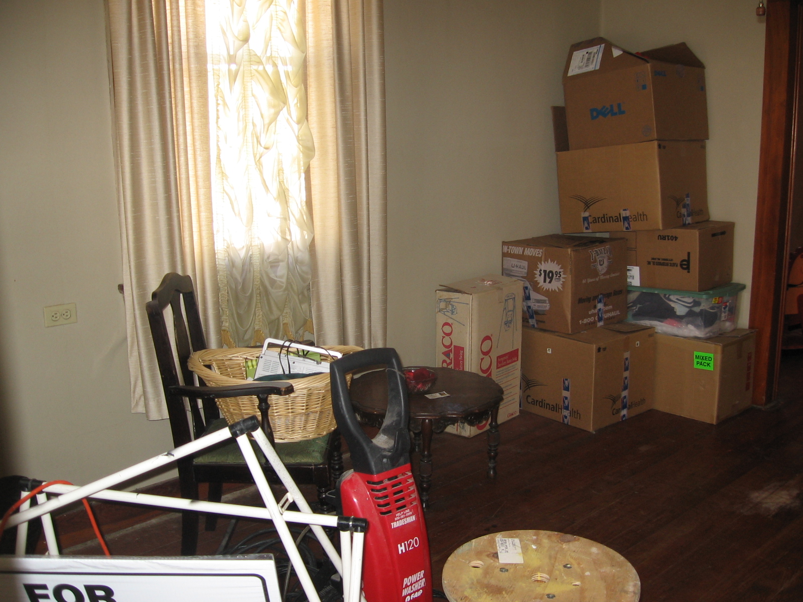 several boxes stacked high in a room with chair, television, coffee table and bike