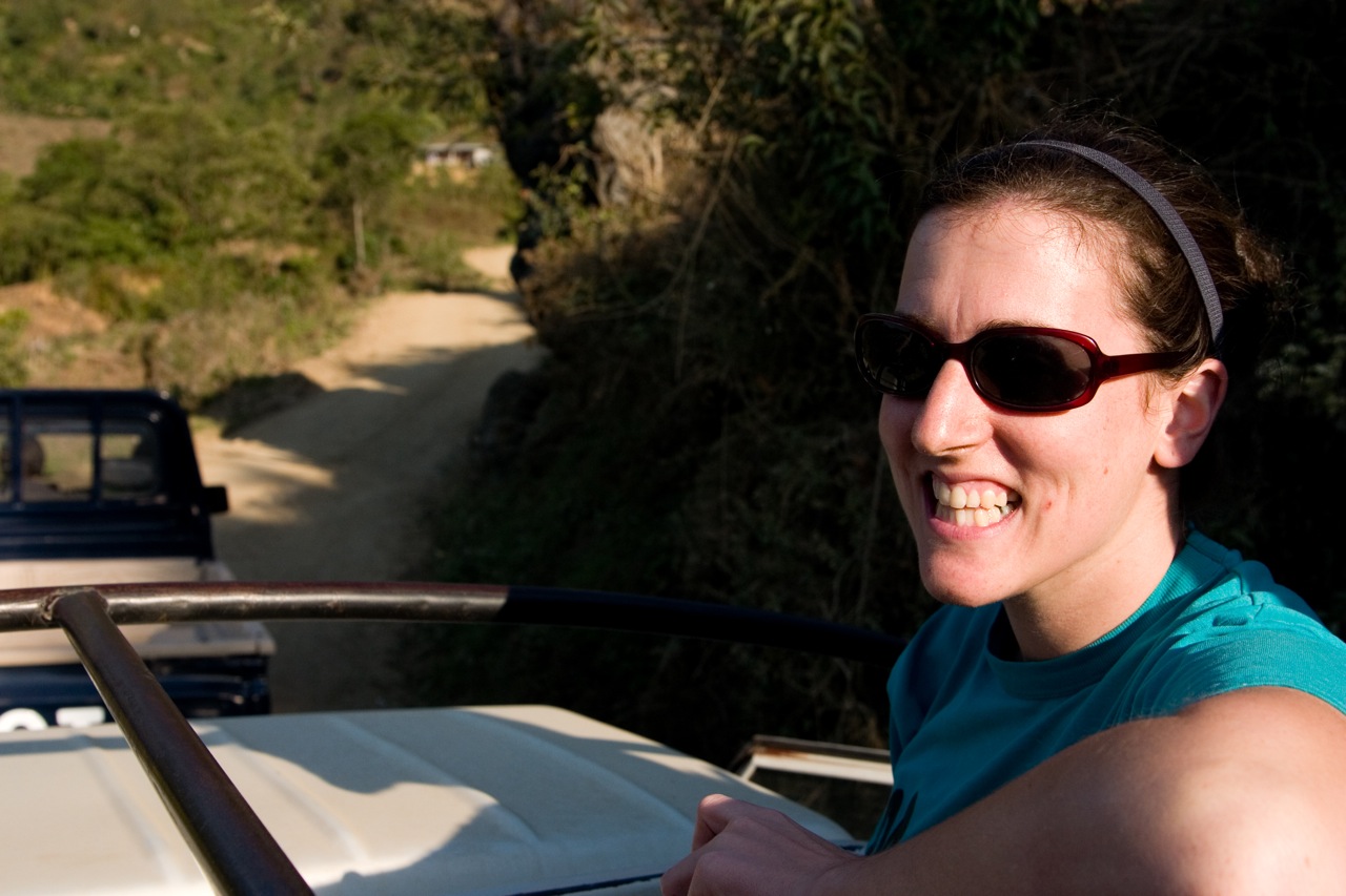 a lady driving a convertible with a jeep in the back