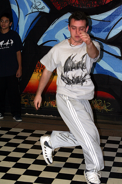 a man standing on a checkerboard floor in front of graffiti covered wall