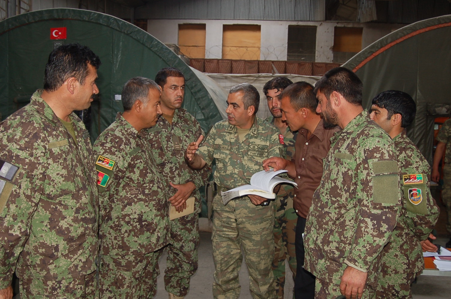 a group of military men in camouflage talking to each other