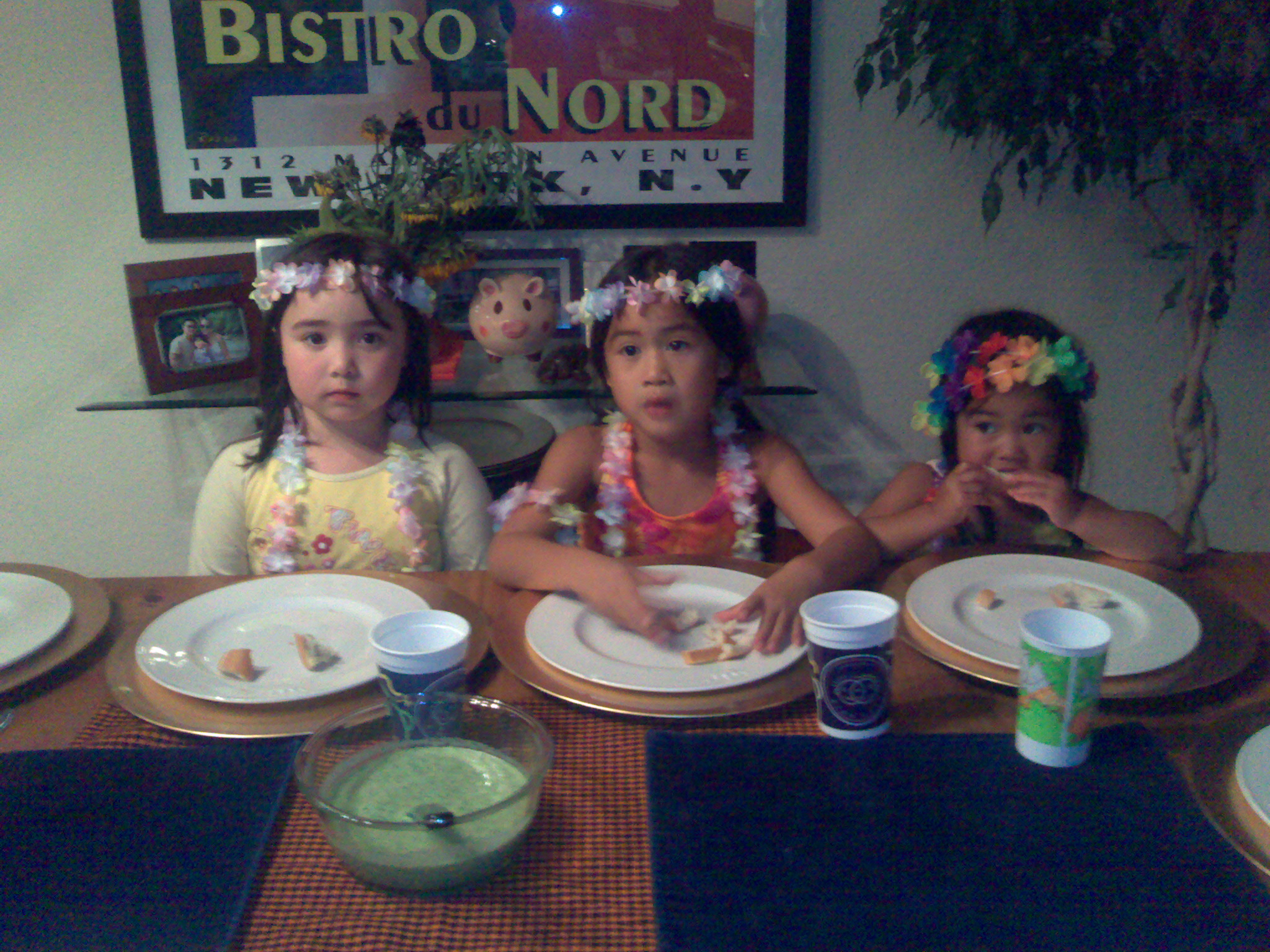 three s sitting around the dinner table eating food