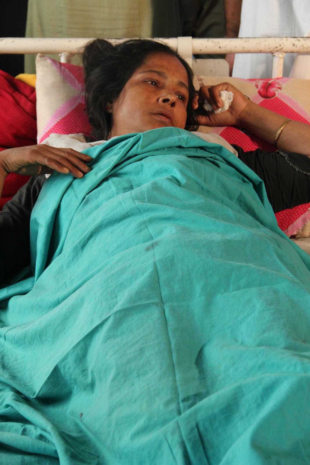 a woman laying in bed on the phone with her arm wrapped around her head