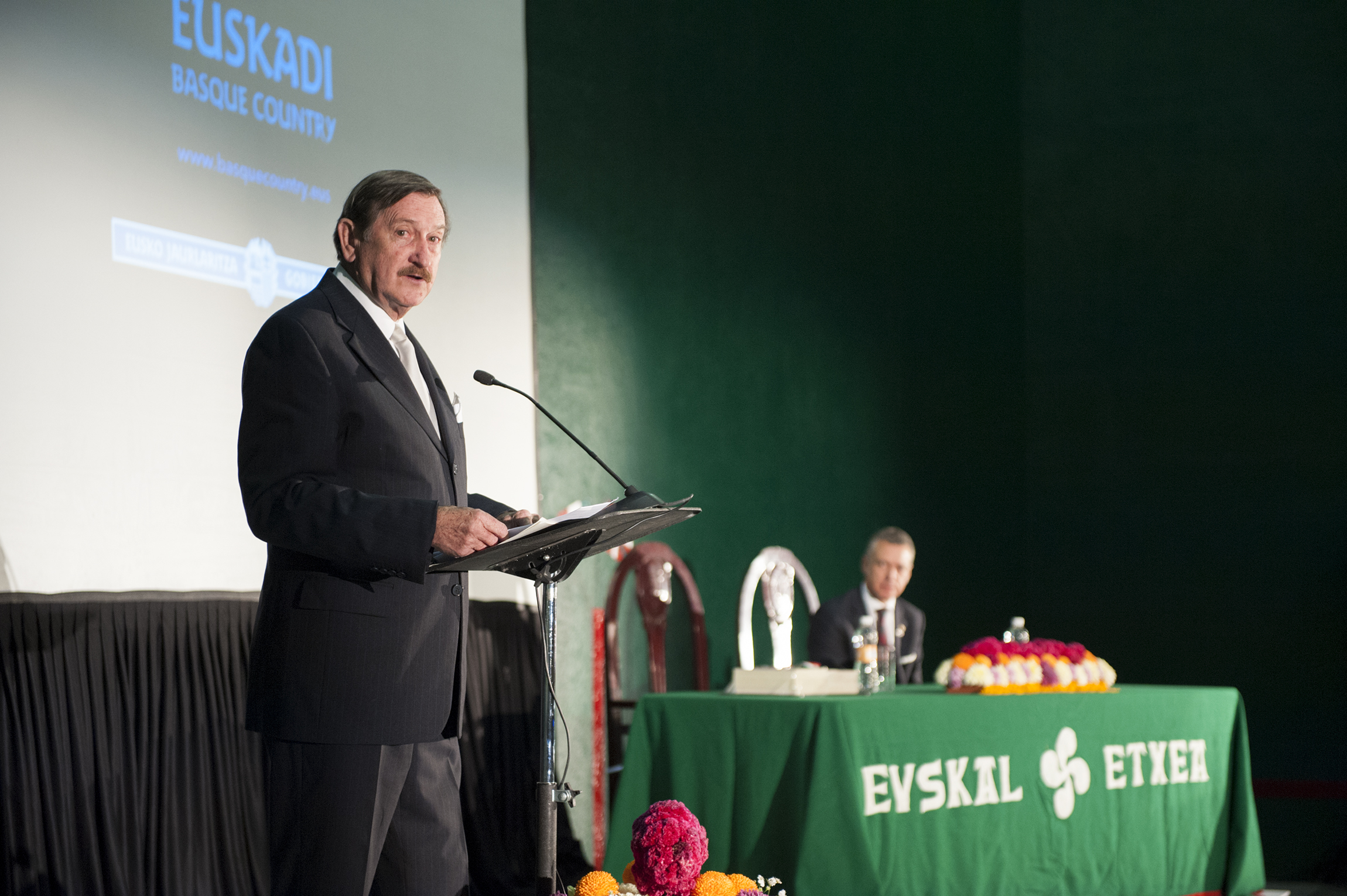 man in business suit speaking at podium during event