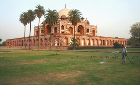 this is an old building with a water spewer going through the grass