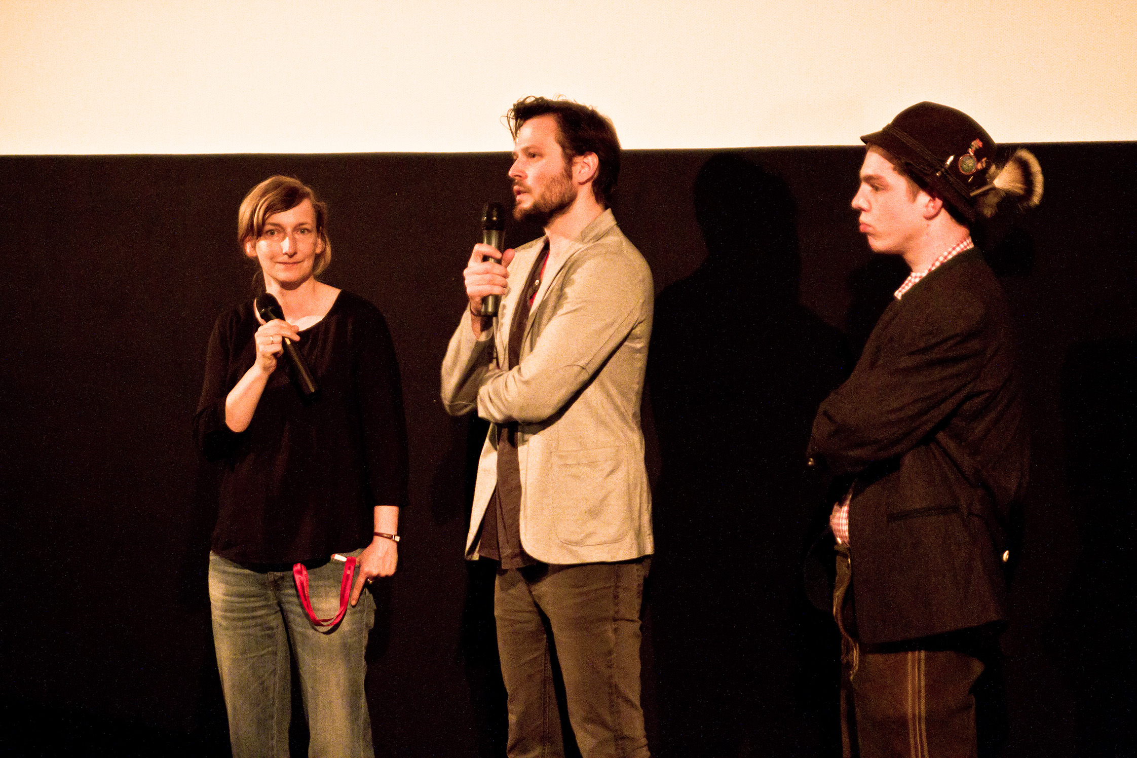 four people are standing on a stage in front of a screen