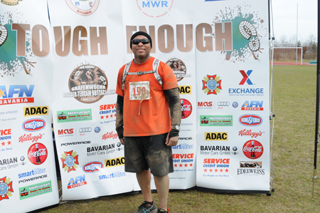 a man standing on a field wearing sunglasses and an orange shirt