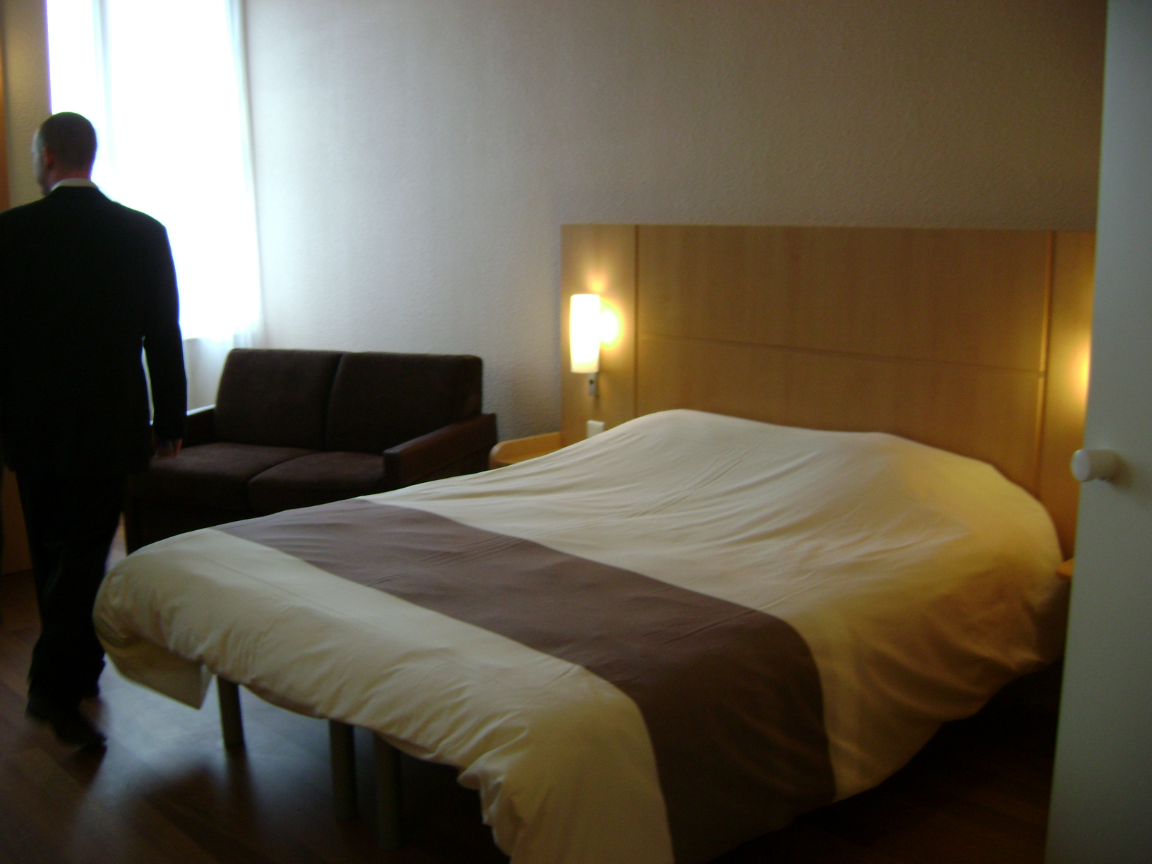 a man standing next to a bed looking at another