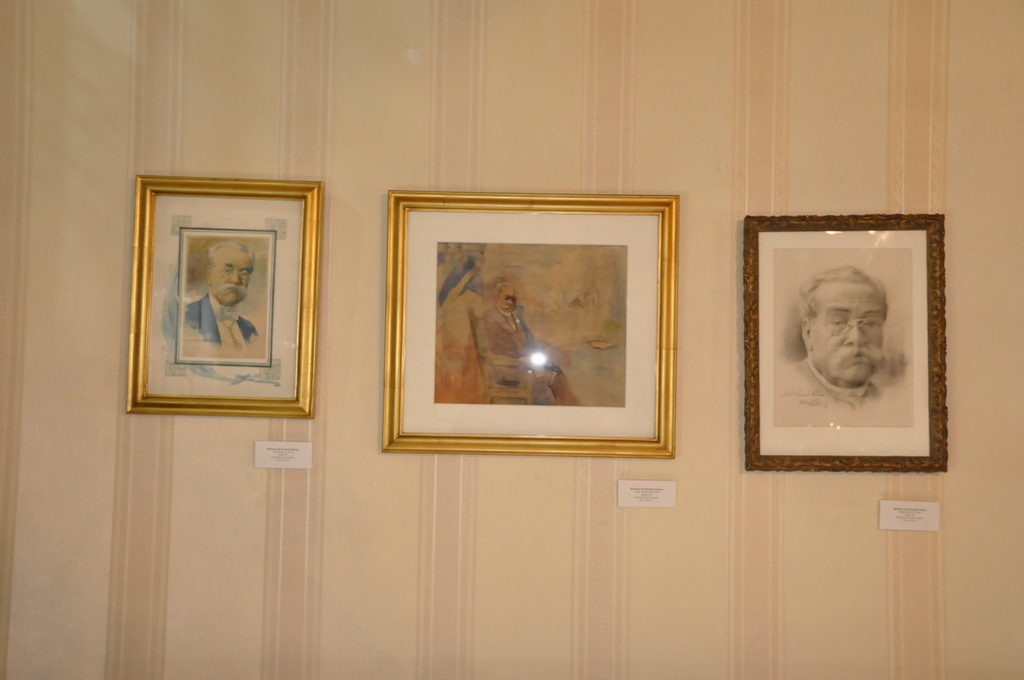 three paintings of famous authors hang on a wall