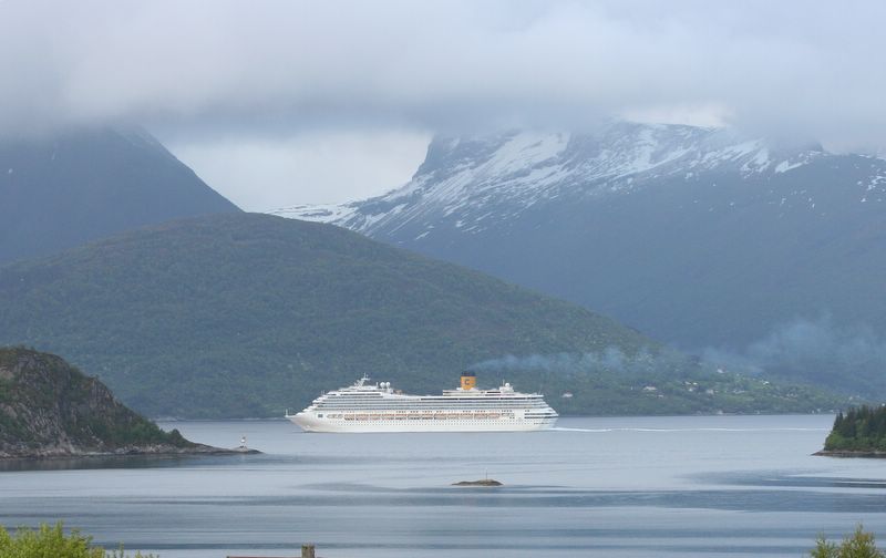 a cruise ship on the water in front of mountains