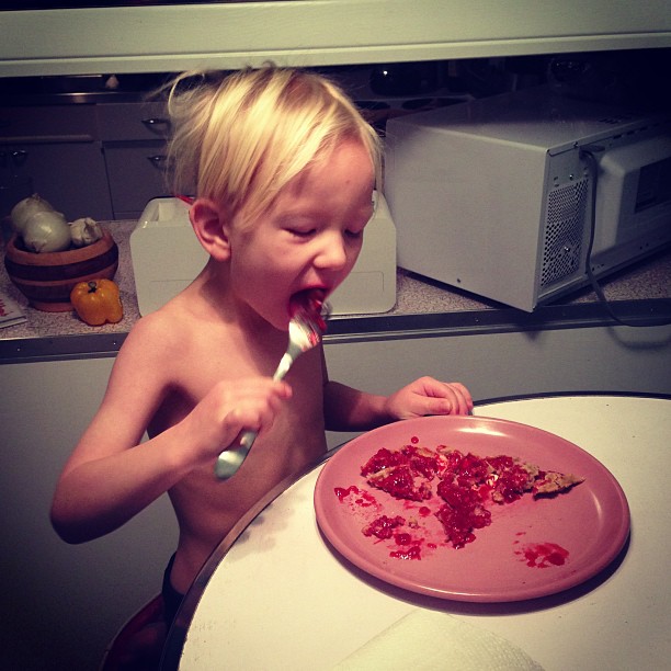 a little boy eating food with a spoon