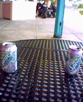 two soda cans sitting on a table outside