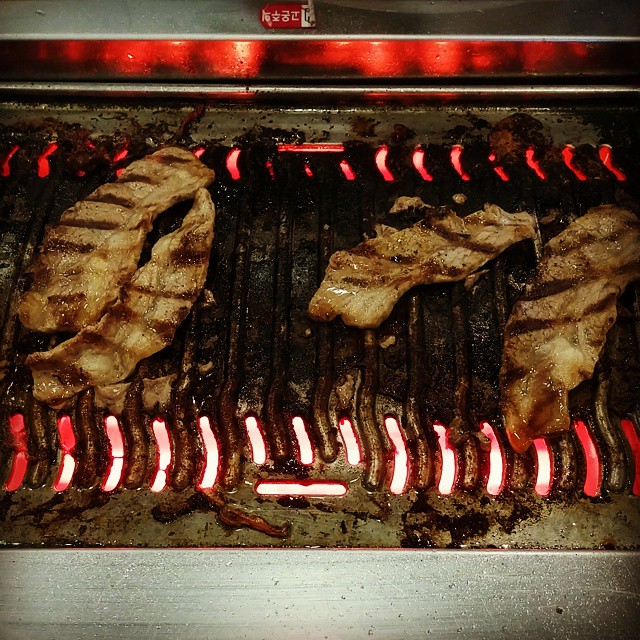 an open grill with some meat cooking on it