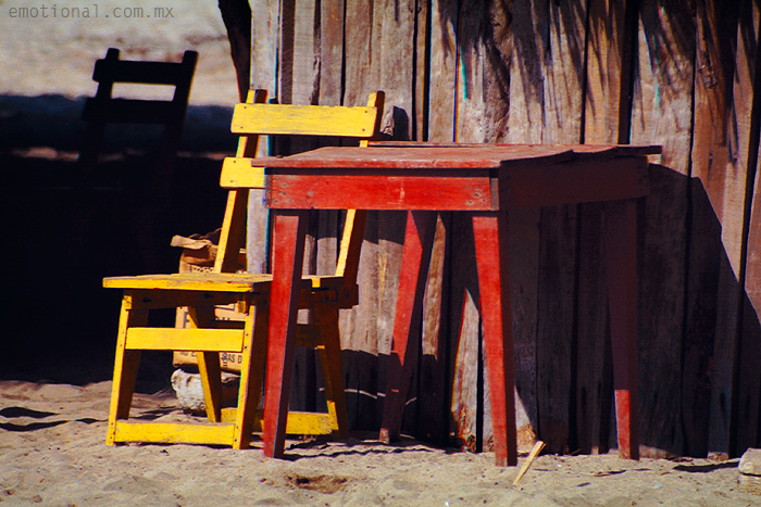 a wooden and yellow chair sit on the beach