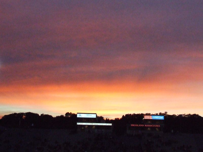 an illuminated scoreboard against an evening sky