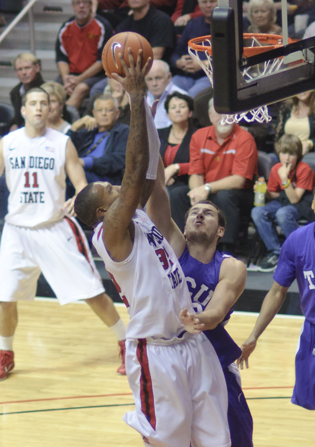 a man is reaching to dunk the basketball during a game