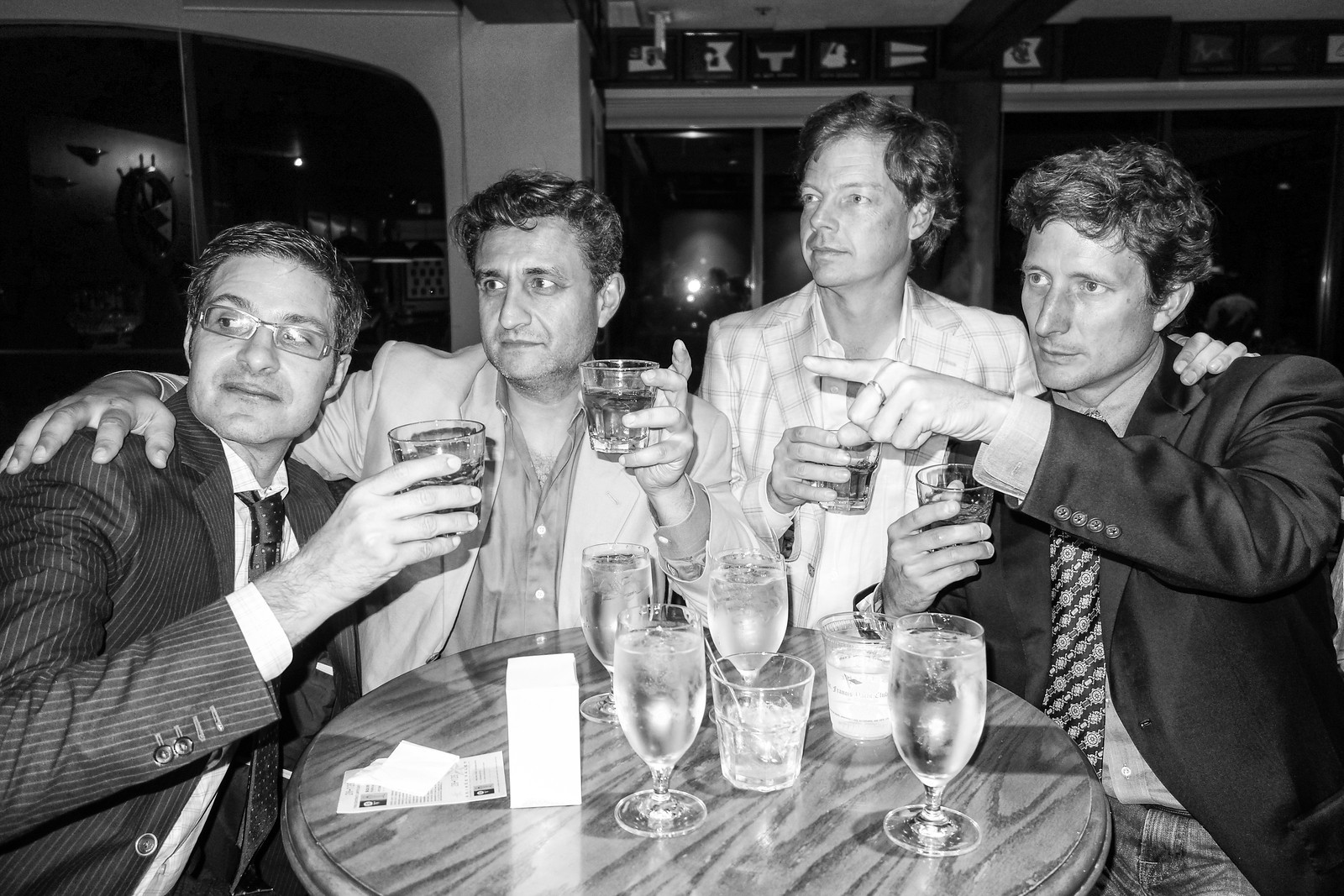 four men posing together with glasses of wine