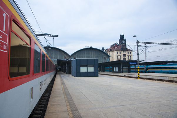 red and white train parked in front of two buildings