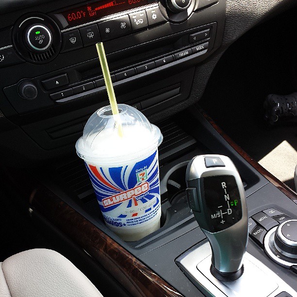 a drink sitting on the car dash with a cell phone holder in front of it