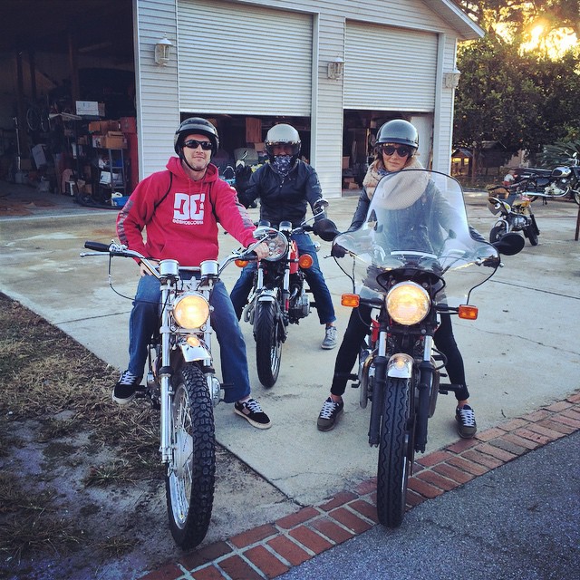 three people on motorcycles on a driveway