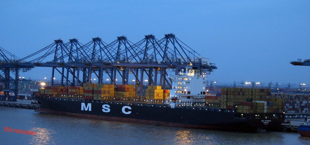 a large cargo ship is at dusk with many other ships