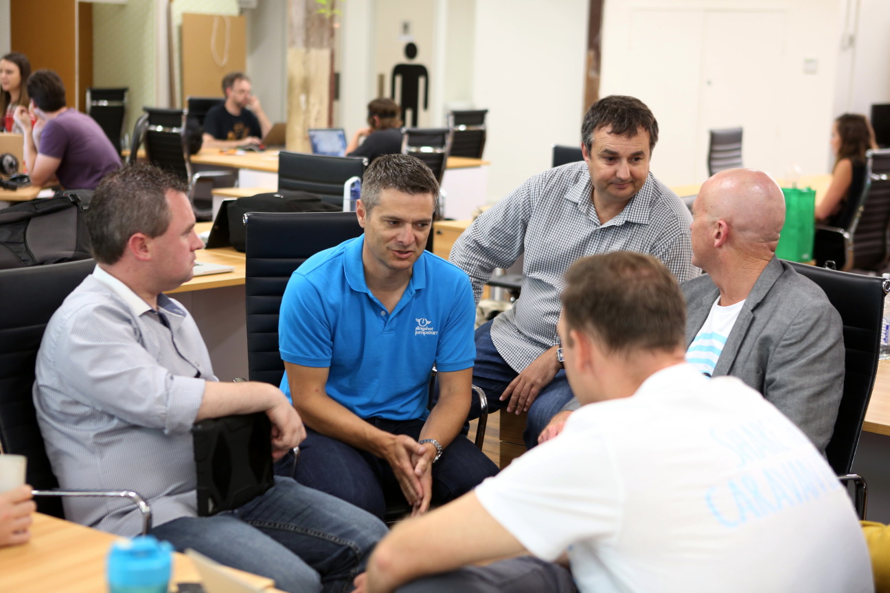 five men sitting in a large room