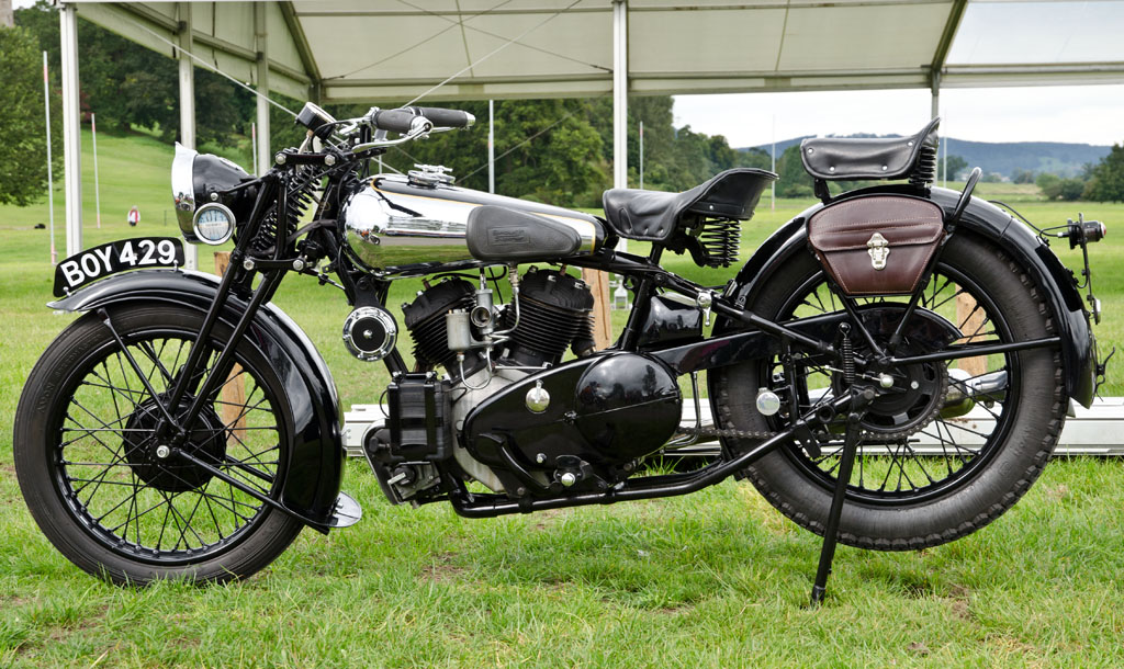 an old motorcycle parked under a tent in the grass