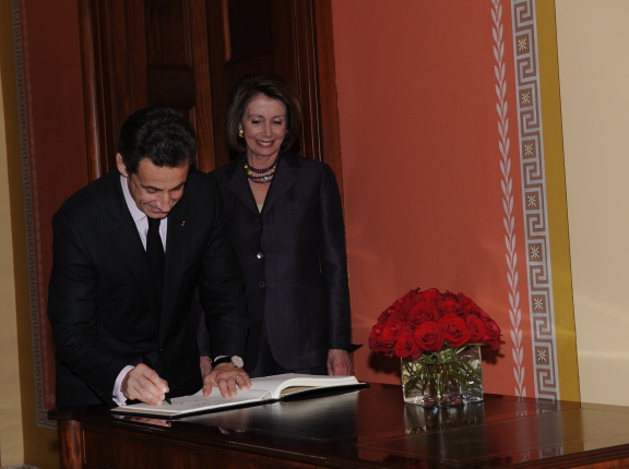 a man and woman signing documents at the end of a wooden desk