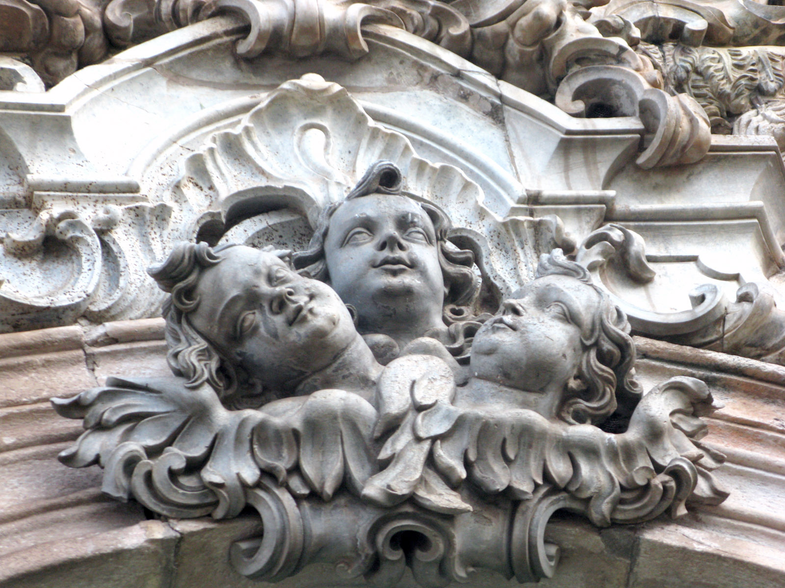 this ornate wall sculpture depicts three s'heads and features architectural elements