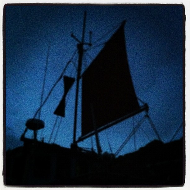 a dark po of a boat against the evening sky