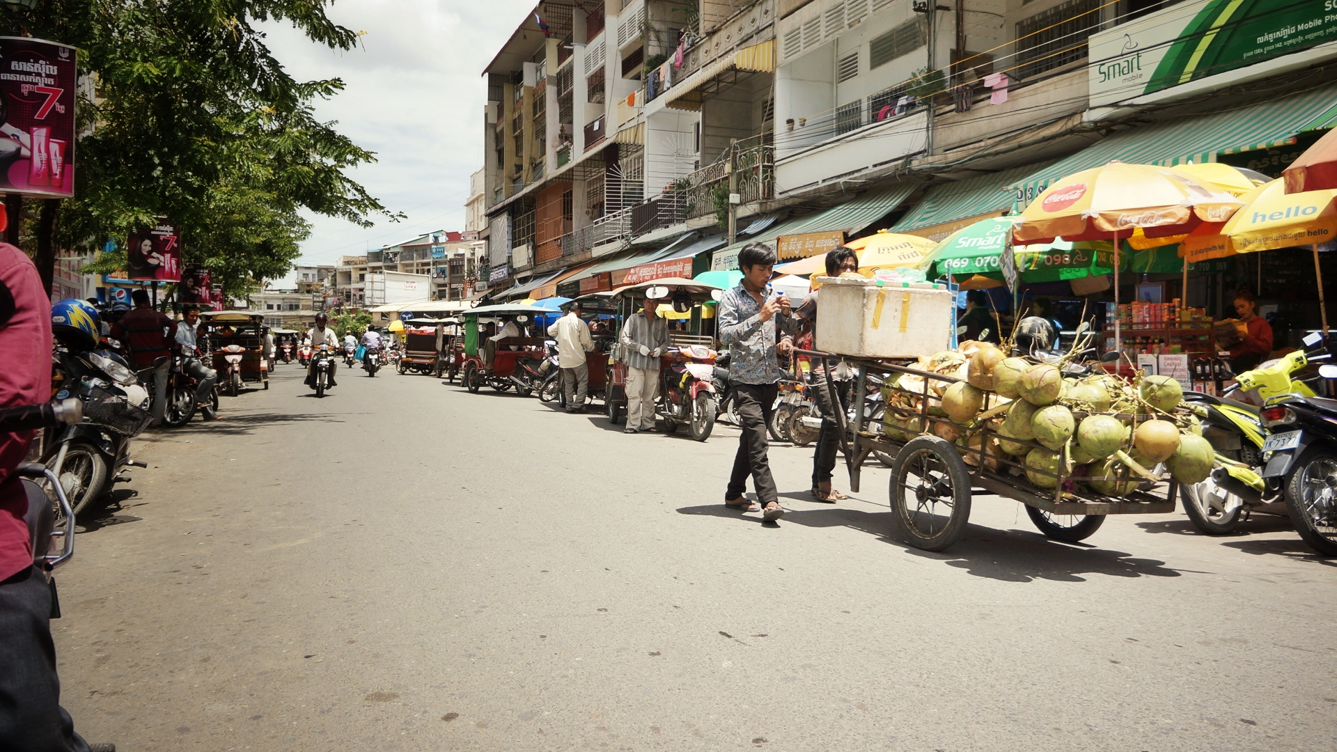 people and carts down the street with vendors