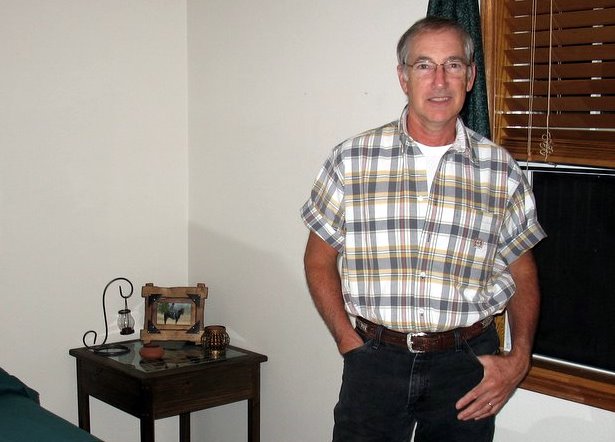 a man standing in a room with a plaid shirt on