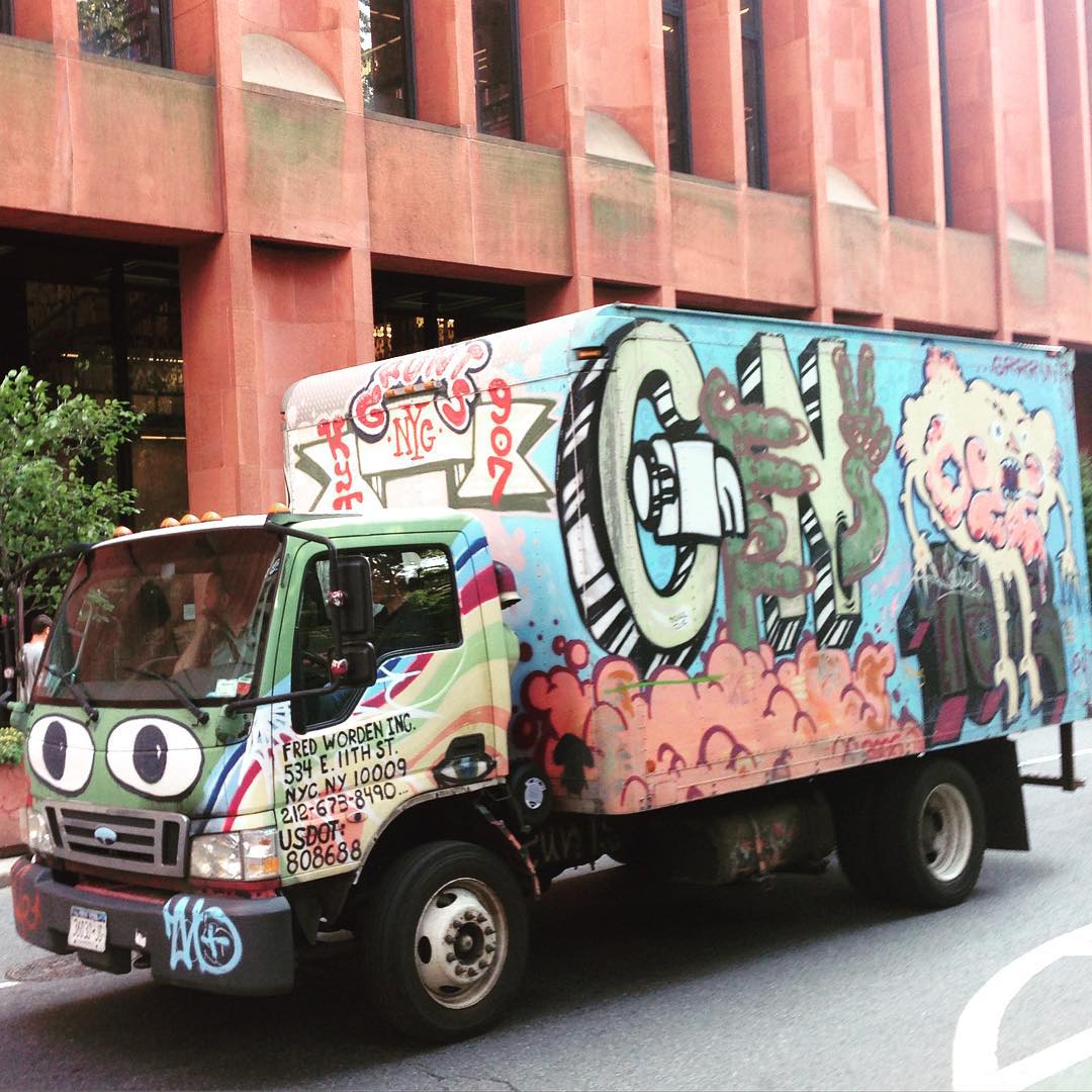 the truck with graffiti is parked on the side of the road