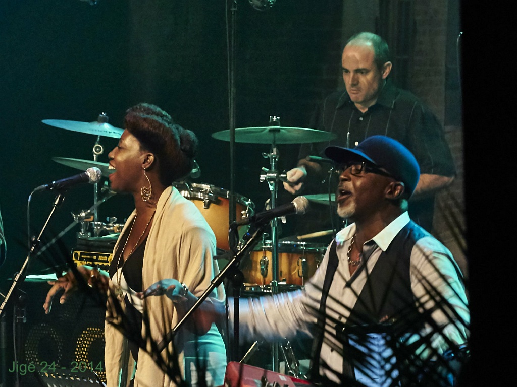 a band playing instruments on stage with a man standing beside him