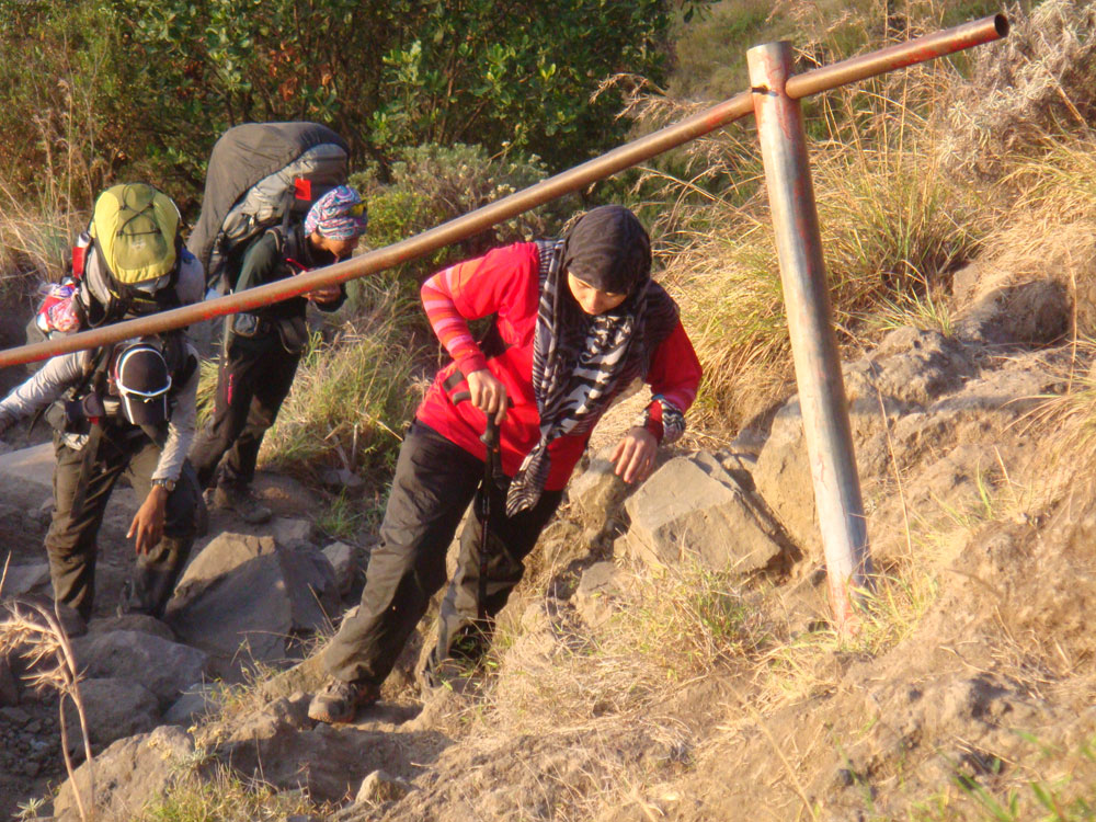 three hikers climbing up stairs of rocks