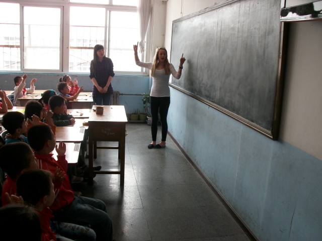 children in school uniforms sitting and writing on the board