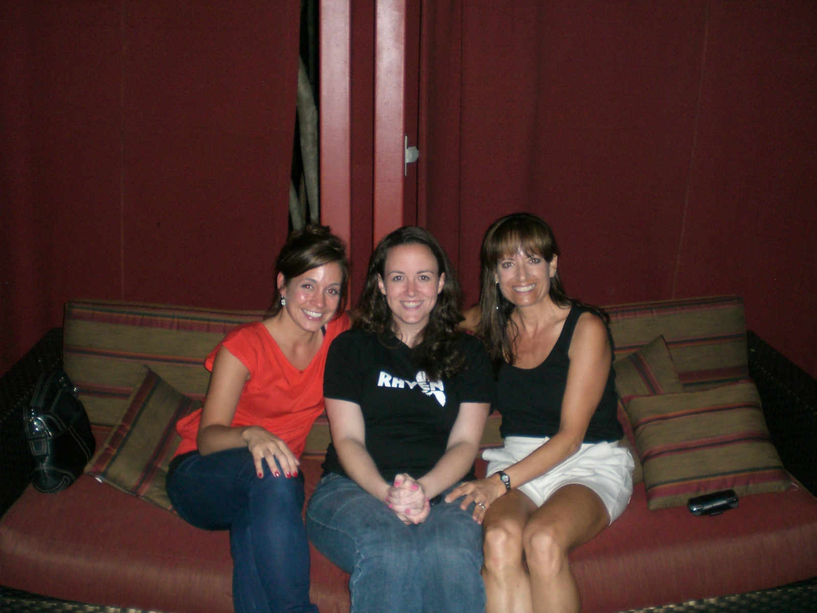 three woman sit on a sofa smiling for the camera