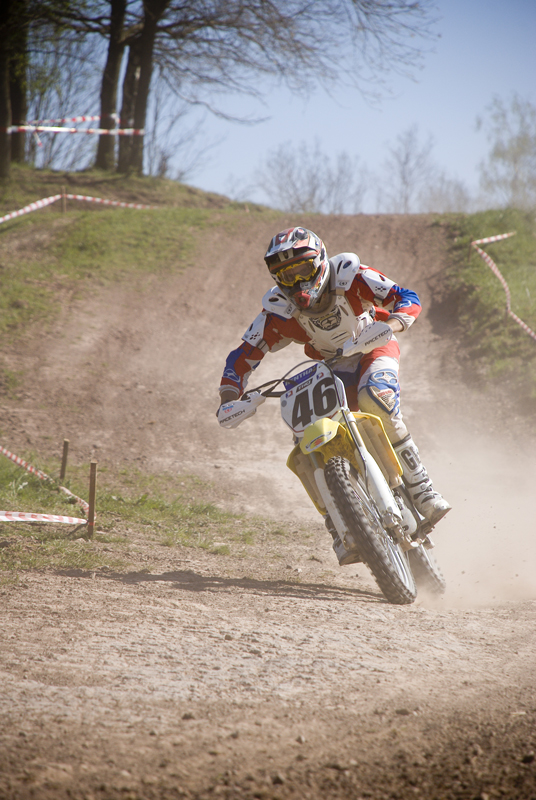 a dirt bike rider in red jersey and white helmet going down the track