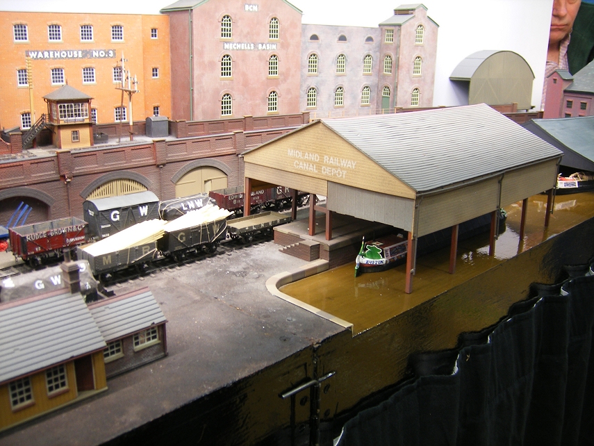 miniature model trains in an indoor setting with buildings and people