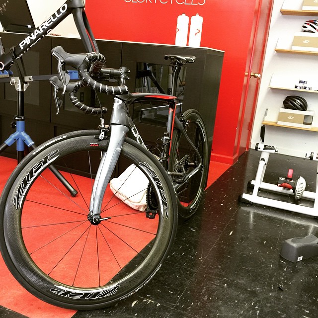 the wheel of a bike and bag of clothing sit behind a store's bike