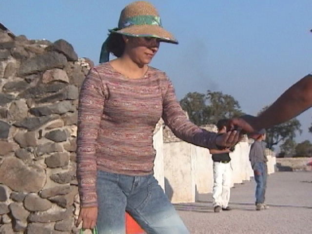 two women in hats hold hands by a stone wall