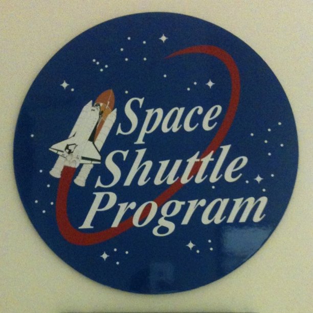 a white and blue space shuttle logo that says space shuttle program