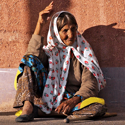 a woman sitting next to a brown wall with a colorful scarf on her head