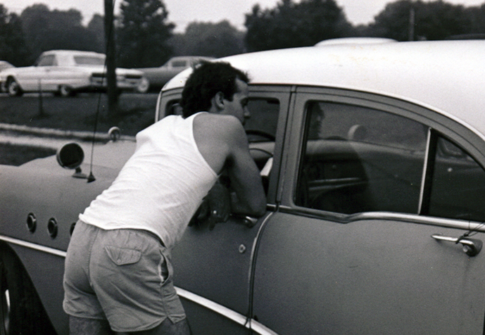 there is a young person standing on the front window of an old car